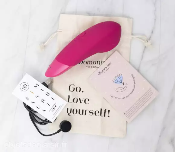Le Womanizer Enhance, son étui, son câble de chargement et sa notice d'utilisation