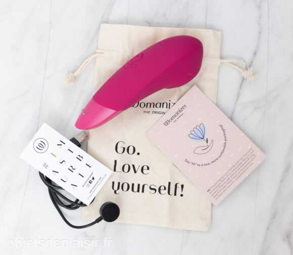 Le Womanizer Enhance, son étui, son câble de chargement et sa notice d'utilisation